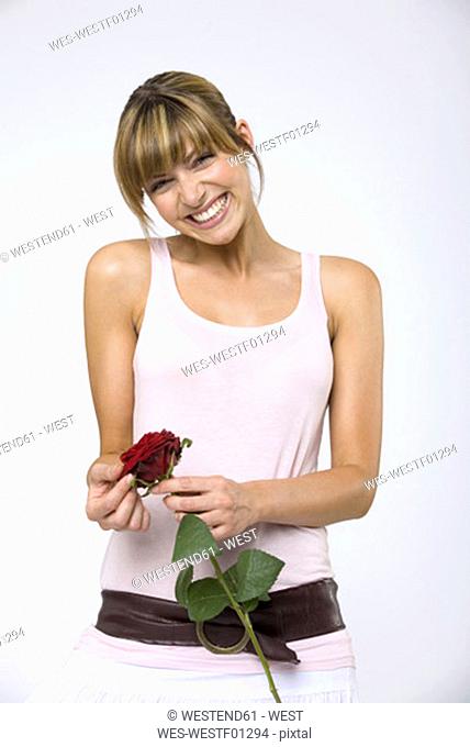 Young woman holding red rose, laughing, portrait, close-up
