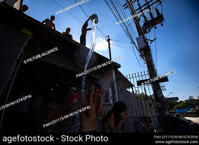 15 November 2023, Brazil, Sao Paulo: Children throw water on people from a rooftop during an extreme heatwave. Even before the start of summer in the southern...