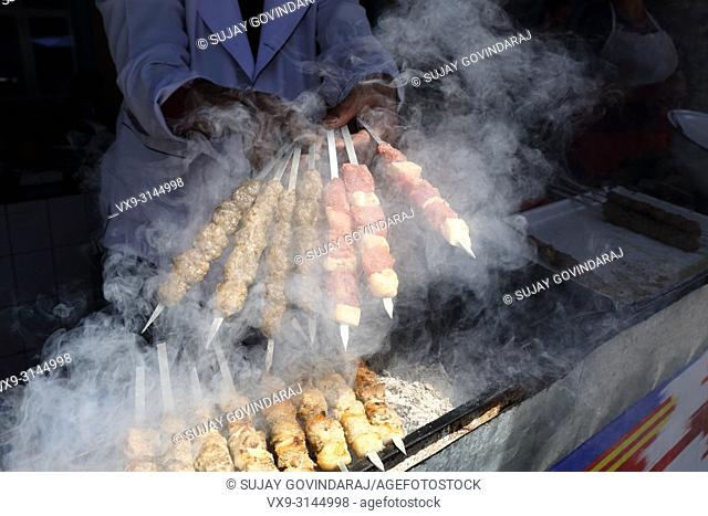 Tashkent, Uzbekistan - May 01, 2017: Shashlik, a regional Uzbek dish is being prepared by an unknown cook in a traditional styled barbeque at food court