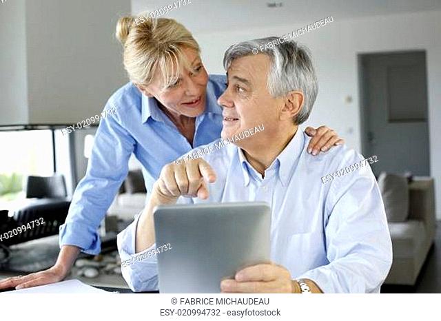 Senior couple looking at bank account on digital tablet