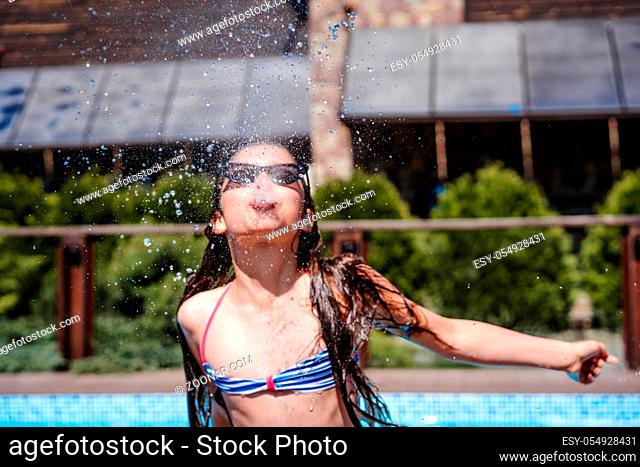 Girl in the pool sprinkles water from her mouth