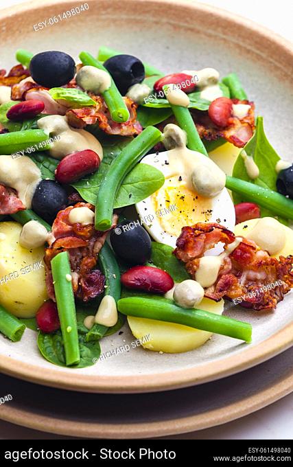 salad of green and red beans with black olives, spinach, boiled egg and bacon