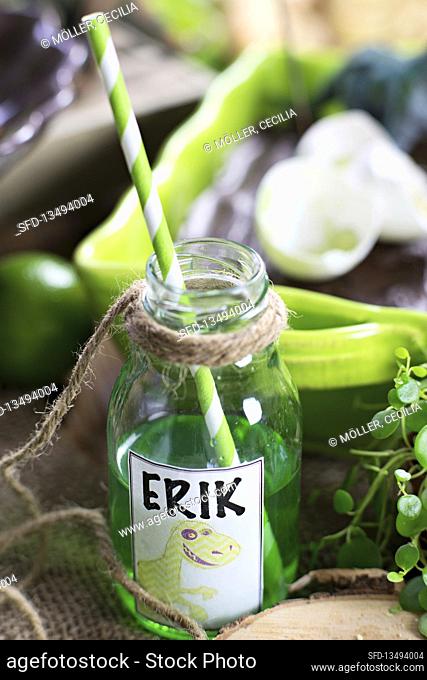 Green drink with straw in bottle for dinosaur party