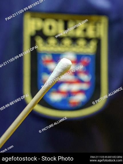 05 November 2021, Hessen, Büdingen: A police employee holds a test stick in front of a Hessian police logo at the Wolfgang Konrad Hall in the Lorbach district...