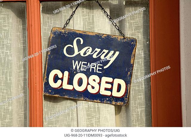 Old fashioned sign, Sorry we're Closed in window of village shop