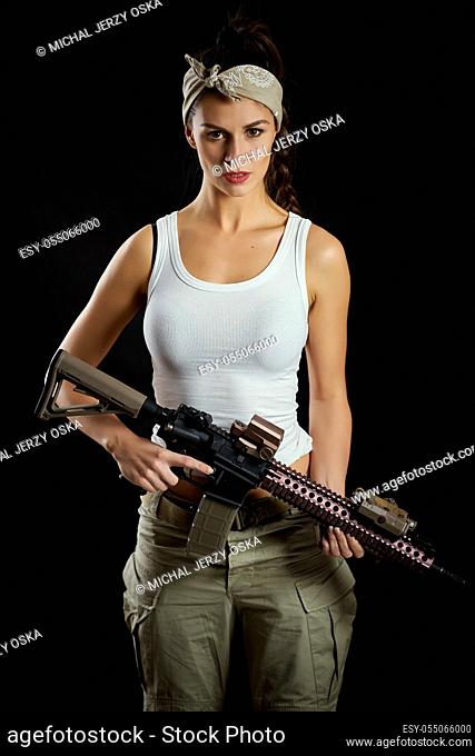 sexy young woman, brunette posing on a black background in a military outfit and a rifle