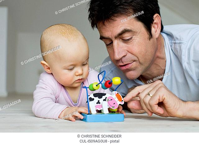 Mature man and baby daughter playing with toy cow