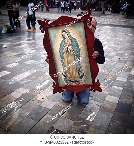 A man holding an image of the Virgin of Guadalupe walks in his knees during the annual pilgrimage to the Our Lady of Guadalupe basilica in Mexico City, Mexico
