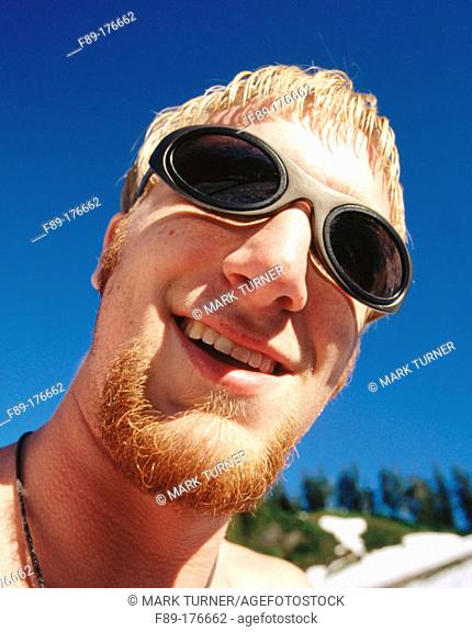Young smiling male face wide angle against blue sky