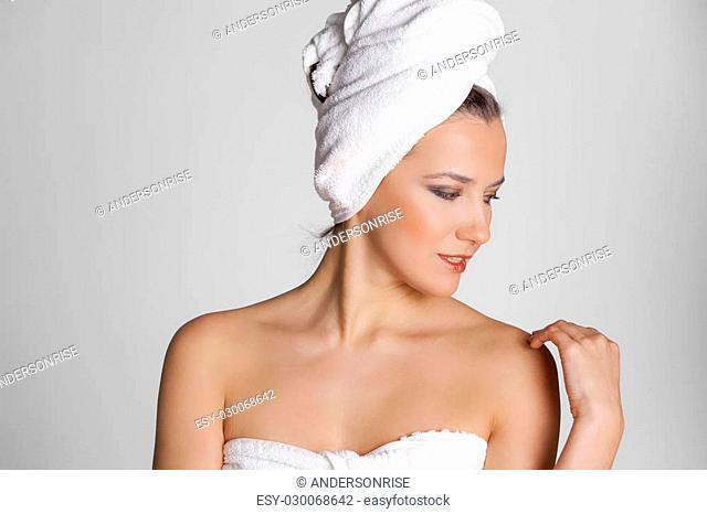 Body Care. Beautiful young woman posing in white towel. Spa, healthcare. isolated on grey background