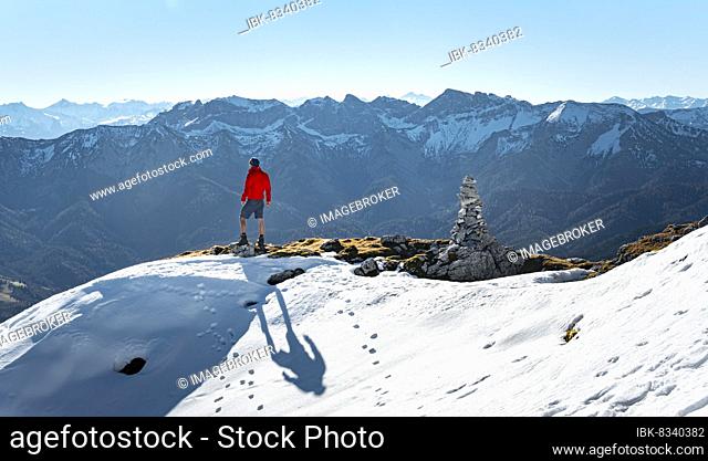 Mountaineer next to a cairn, in front of snowy mountains of the Rofan, hiking trail to the Guffert with first snow, in autumn, Brandenberg Alps, Tyrol, Austria