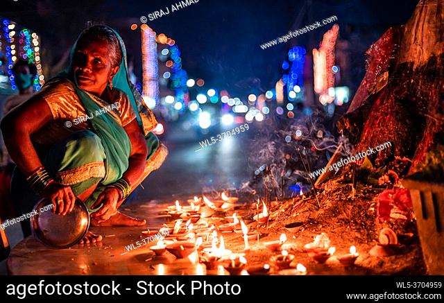 Closeup Middle-aged woman offers prayers with incense stick on the night of Diwali outdoors