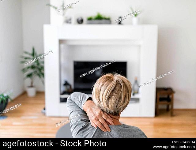 Senior woman in the living room with neck pain