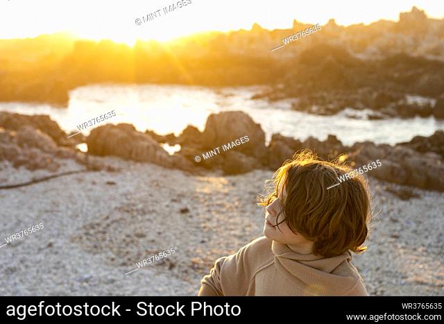 A young boy playing on the beach among the rocks on the beach at De Kelders