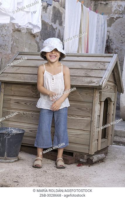 happy little girl outdoors in frot of a doghouse