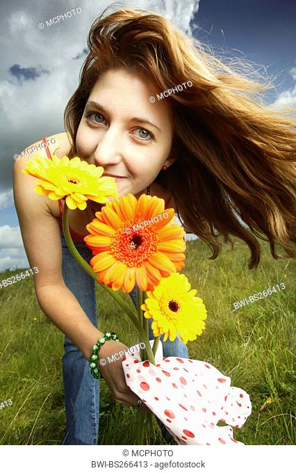 Barebeton Daisy, Gerbera, Transvaal Daisy, Gerbera Daisy Gerbera jamesonii, young girl in summer clothes standing in a meadow with waving hair and a smile...