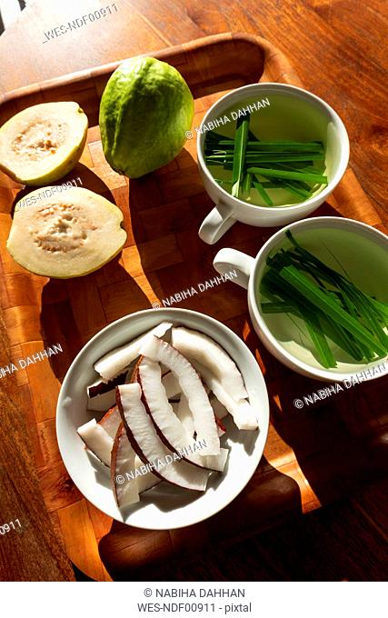 Seychelles, wooden tray with guava, bowl of fresh coconut slices and cups of lemongrass tea