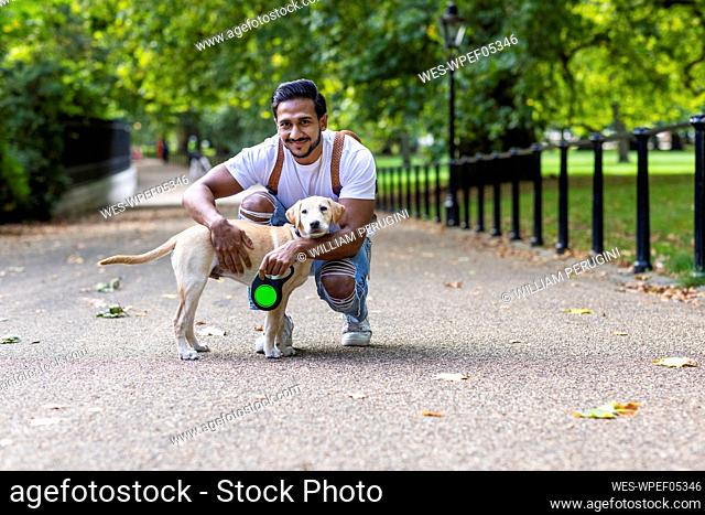 Smiling man stroking dog on road in park