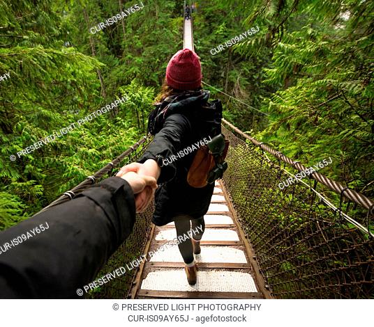 Woman on Lynn canyon suspension bridge holding mans hand, North Vancouver, British Columbia, Canada