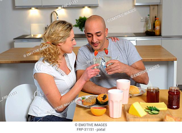 Happy couple clinking champagne glasses in kitchen