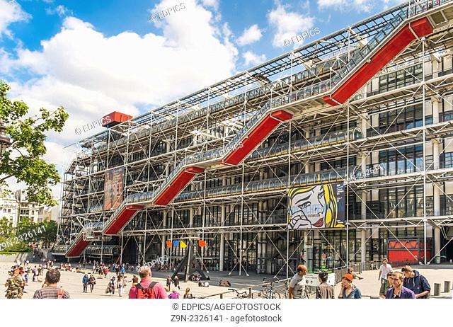people in front of georges pompidou centre, on the facade of the building a poster for an exhibition of works by american artist roy lichtenstein