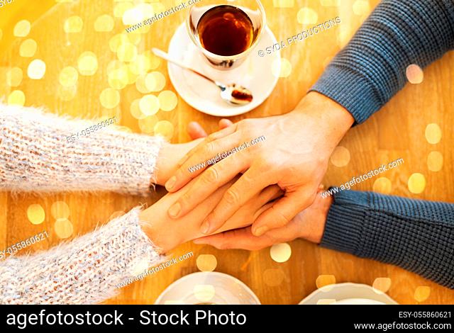 close up of couple holding hands at restaurant