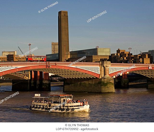 England, London, Blackfriars Bridge, A sightseeing boat travelling under Blackfriars road bridge with the towering chimney of the Tate Modern in the background