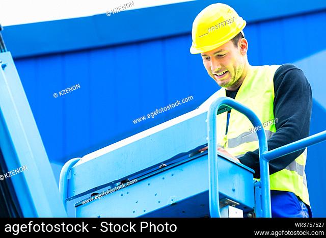 Construction workers or crane driver on site driving hydraulic lifting ramp with control desk