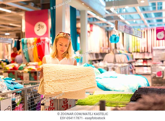 Pretty, young woman choosing the right item for her apartment in a modern home decor furnishings store