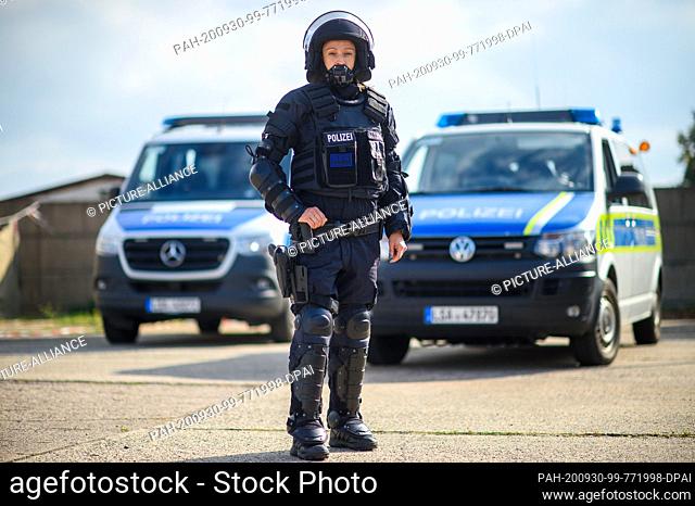 30 September 2020, Saxony-Anhalt, Magdeburg: A policewoman equipped with a new body armour (KSA) stands in front of police vehicles