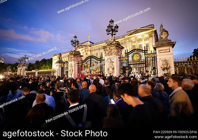 09 September 2022, Great Britain, London: Hundreds of people walk slowly past the main entrance at Buckingham Palace decorated with flowers and messages of...