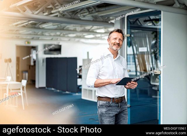 Male professional holding digital tablet while standing in office
