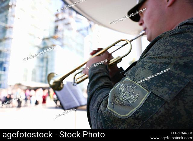 RUSSIA, LUGANSK - OCTOBER 14, 2023: A military band member plays a trumpet outside the Church of Our Lady of Tenderness during the Christian feast of the...
