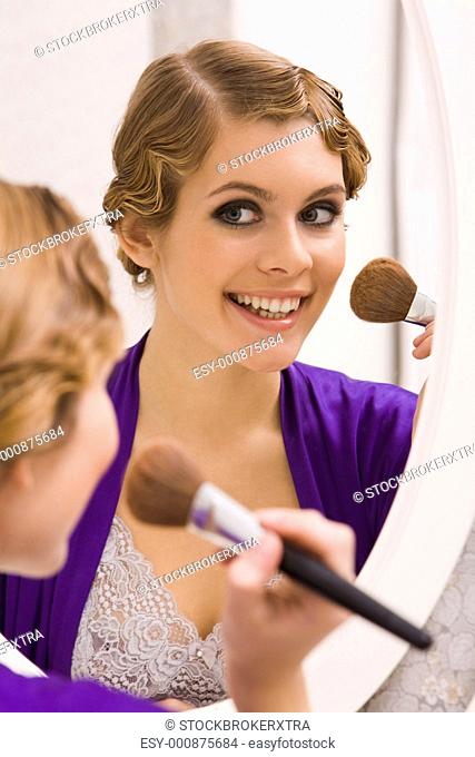 Image of pretty female looking in mirror and doing makeup
