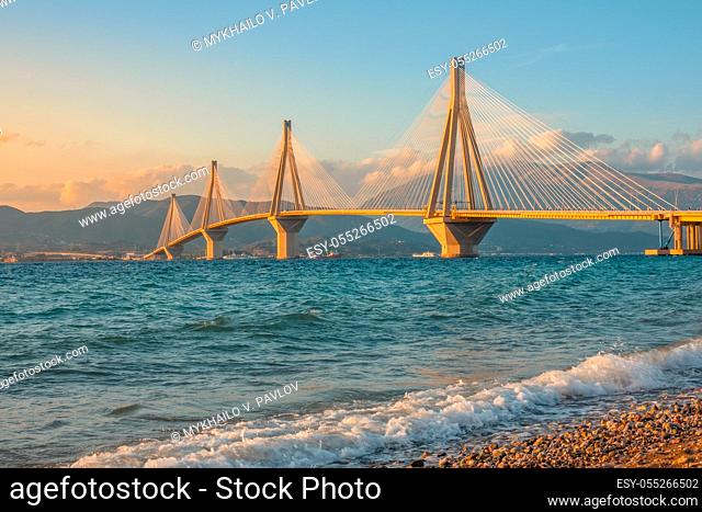 Greece. Gulf of Corinth and Rio Antirio bridge. Sunset lighting on a pebble beach