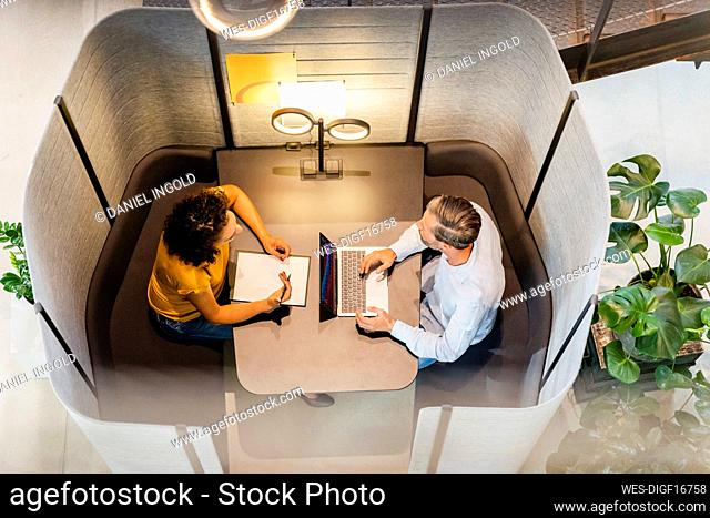 Businesswoman discussing with colleague at desk