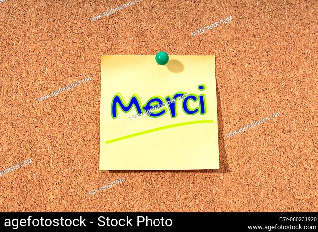 Thanks word in french language on yellow note on cork board