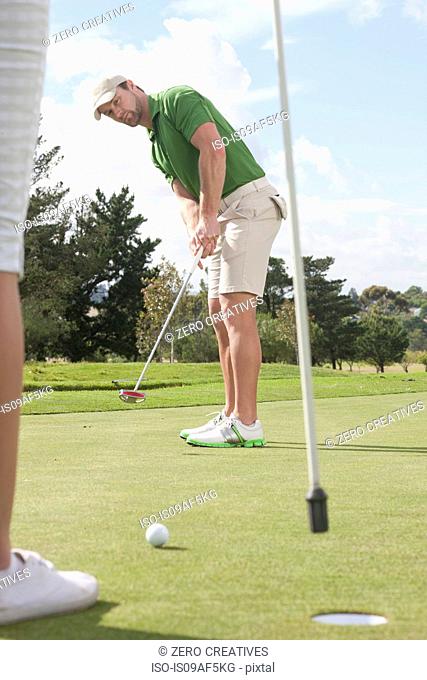 Young male golfer putting on golf green
