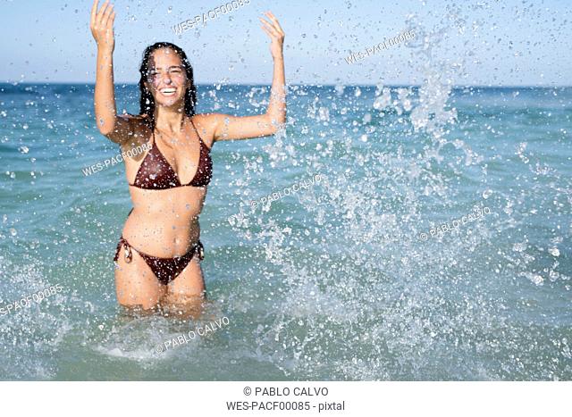 Happy carefree young woman splashing in the sea