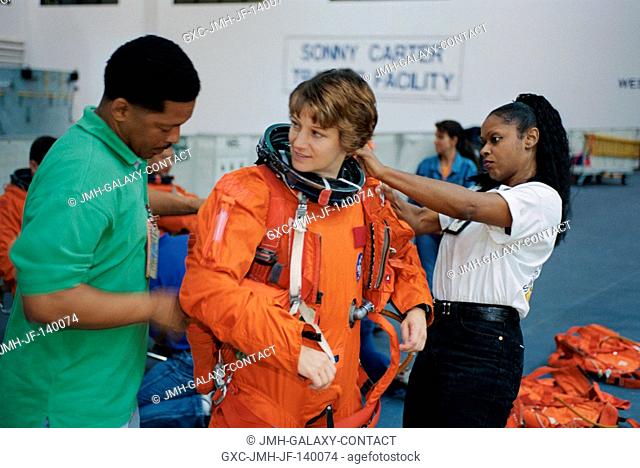 Astronaut Eileen M. Collins, STS-114 mission commander, dons a training version of the shuttle launch and entry suit, prior to the start of a mission training...