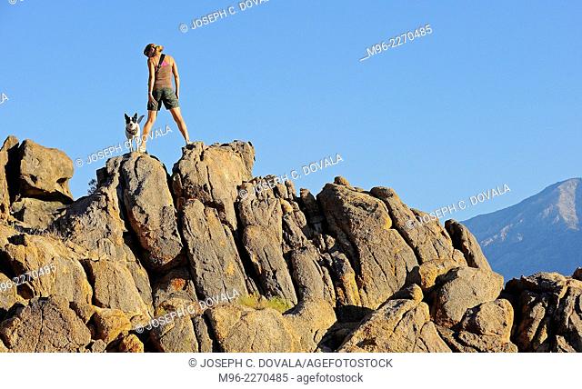Woman climbing rocks with dog, Alabama Hills, California, USA
