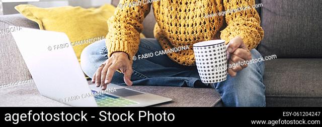 Banner header modern woman at work writing on laptop computer at home sitting on the sofa and drinking a coffee