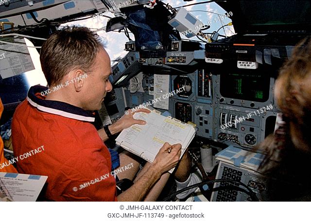 Astronaut Joe F. Edwards Jr., STS-89 pilot, highlights important data on a checklist while temporarily occupying the commander's station on the port side of the...