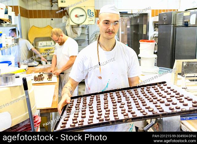 PRODUCTION - 13 December 2023, Thuringia, Erfurt: Baker Louis Braun carries a tray full of cookies to the oven in the Lobenstein bakery and confectionery