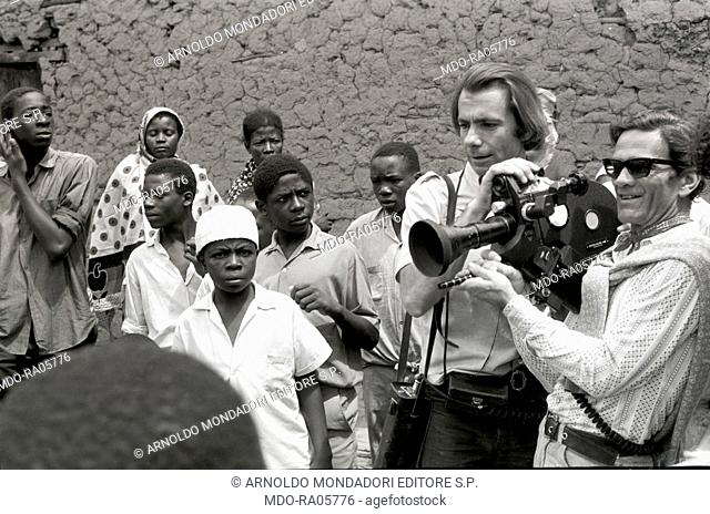Italian writer and director Pier Paolo Pasolini surrounded by many African children and holding a camera on the set of the documentary Notes for an African...