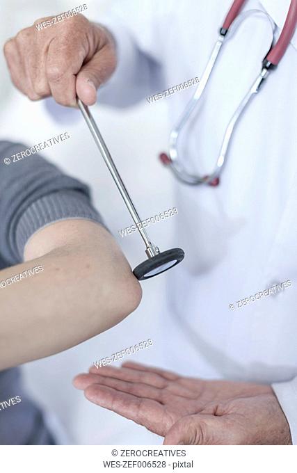 Doctor tapping patient with reflex hammer
