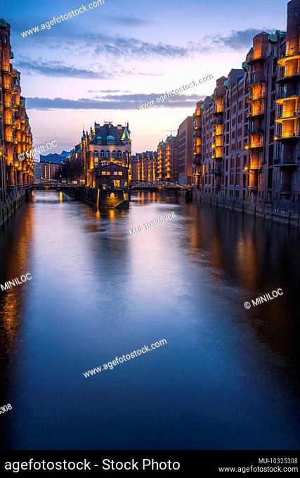 Historic warehouse district in Hamburg, old harbor with water palace park during the blue hour, Germany, Europe
