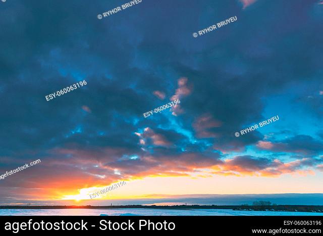 Natural Sunset Sunrise Over Field Or Meadow. Sun Sunshine In Colorful Sky Over Winter Snowy Ground. Landscape Under Scenic Sky At Sunset Dawn Sunrise