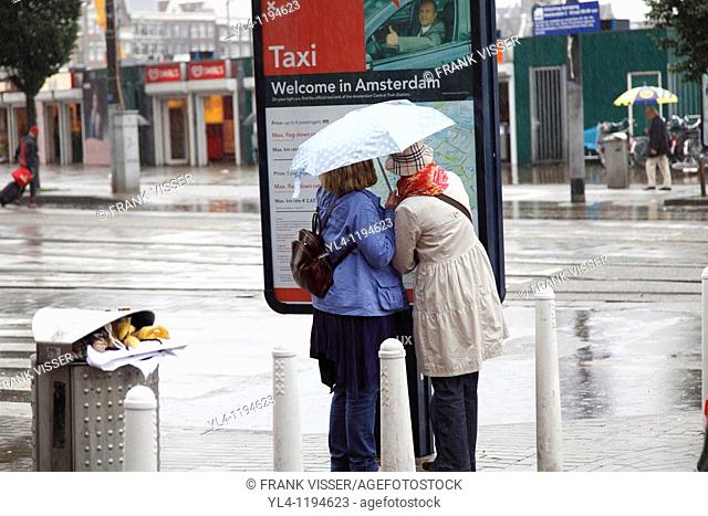 Tourists looking on a map of Amsterdam during a rainy day, The Netherlands