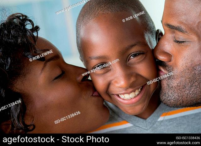 Mother and father kissing son on cheeks